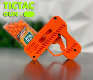 A 3D printed "Tic Tac Gun." The "clip" is an upside-down box of Tic Tacs. The orange plastic gun has a lever to load the Tic Tac and a trigger to shoot it.